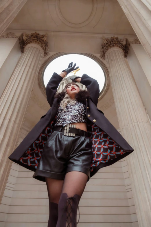 woman with boots and jacket posing in front of pillars