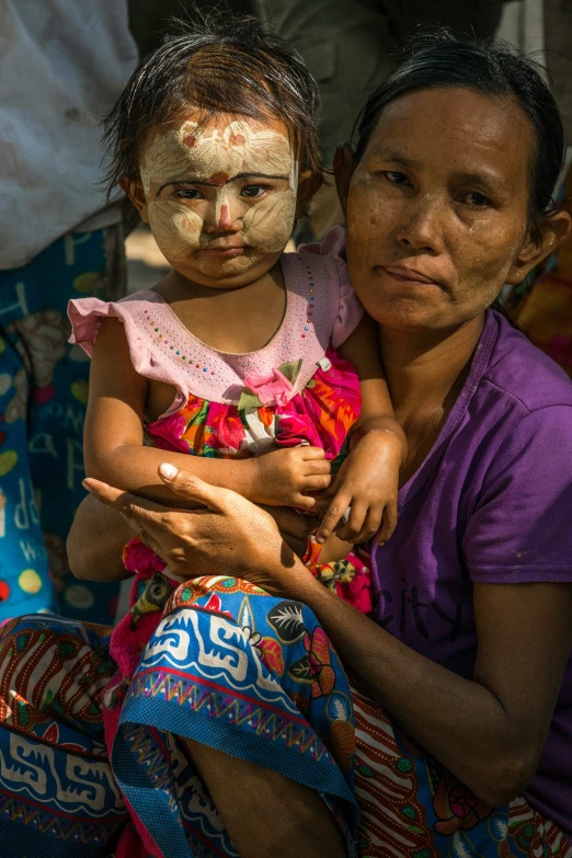 a woman holding a baby while wearing a mask