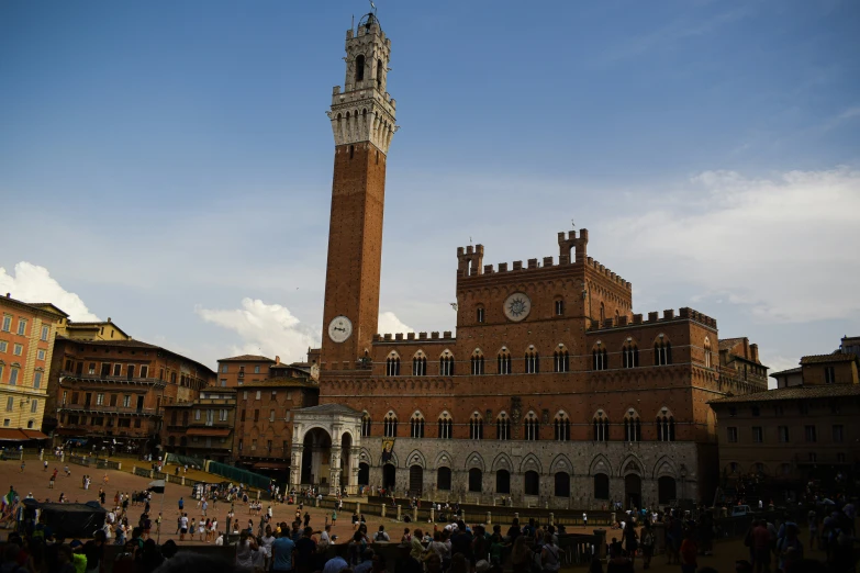 people are outside a building with a large clock tower