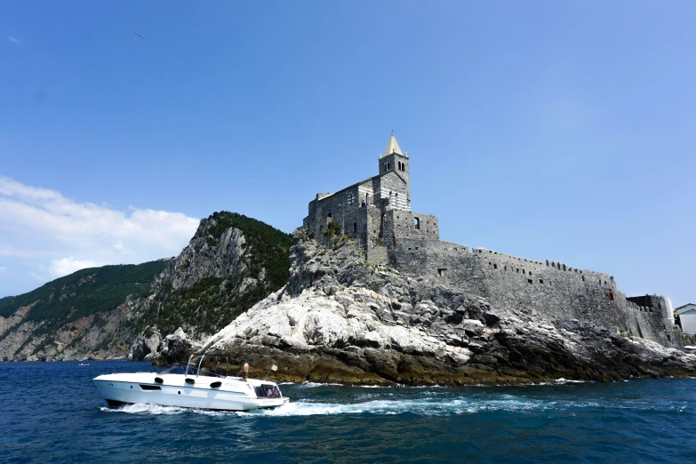 a boat on water next to an island with a church on it