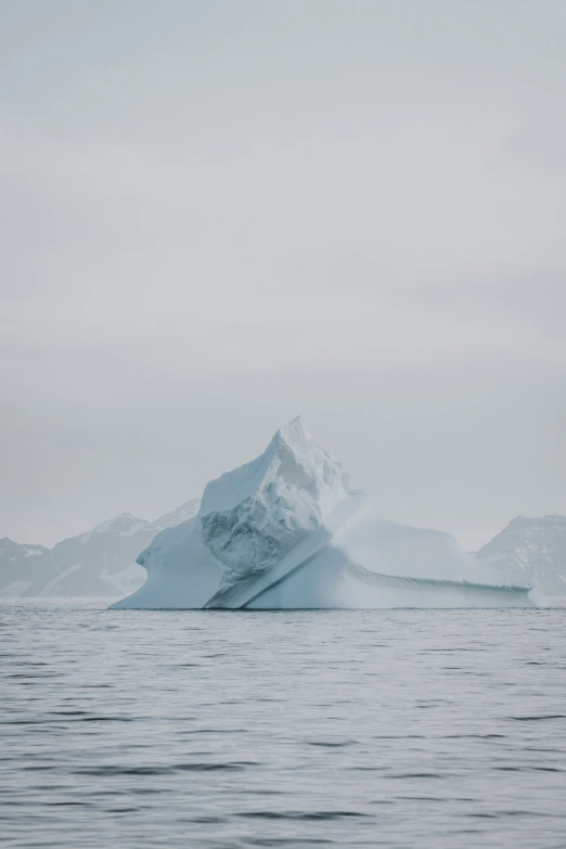 an iceberg floating in the water next to snow covered mountains