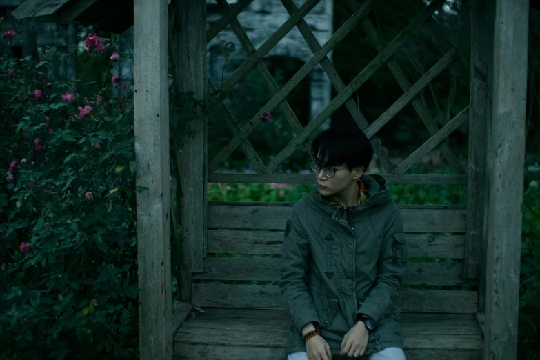 a man sitting on a wooden bench surrounded by greenery