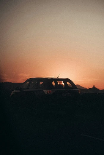 a black suv parked in a field at sunset