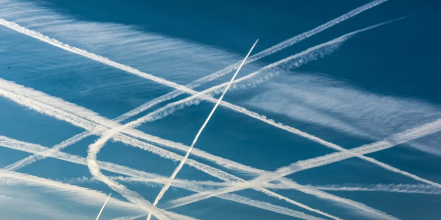 some air planes in sky leaving a series of contrails behind them