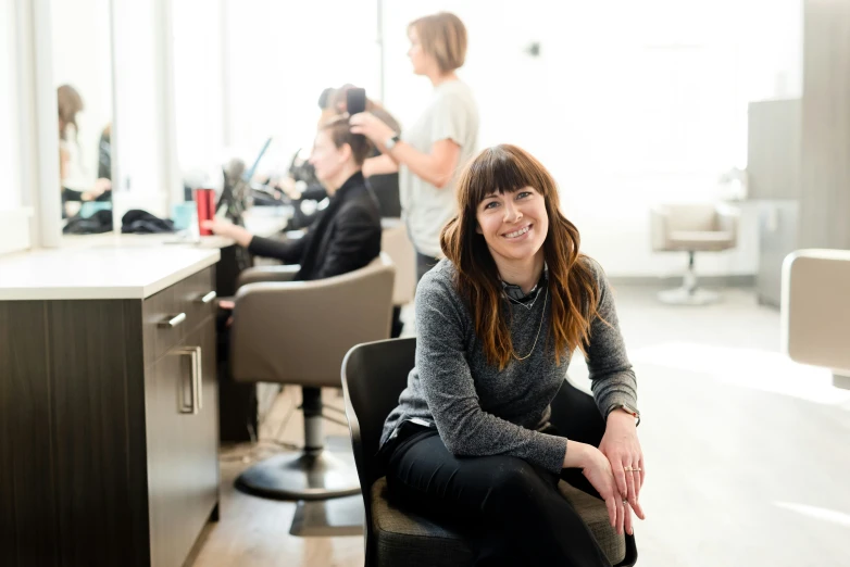 a woman is sitting at a hair salon