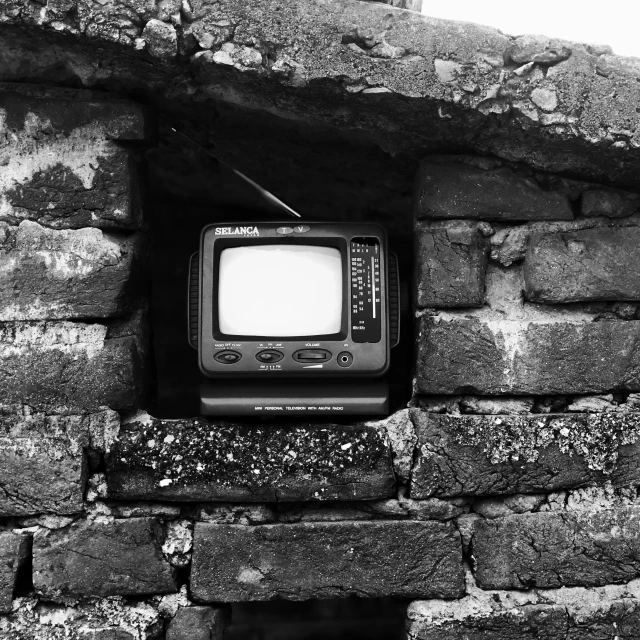 a small tv that is sitting in a stone wall