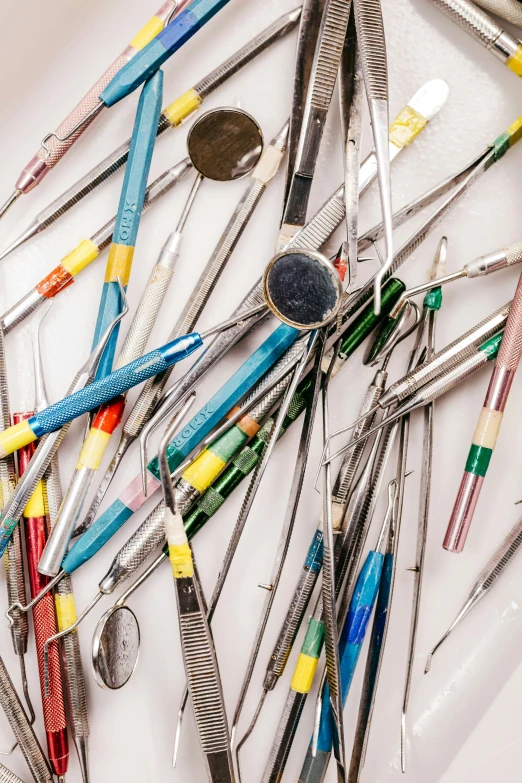 a large assortment of tools like instruments lie on a white surface