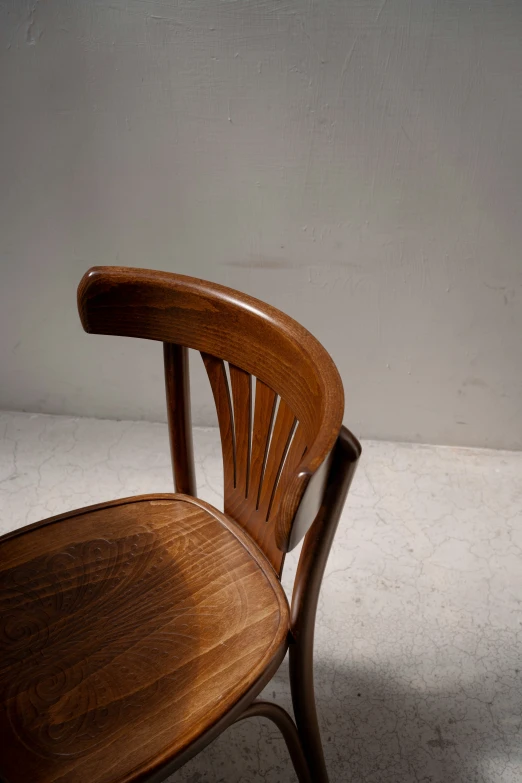 a wooden chair sits on a floor next to a wall