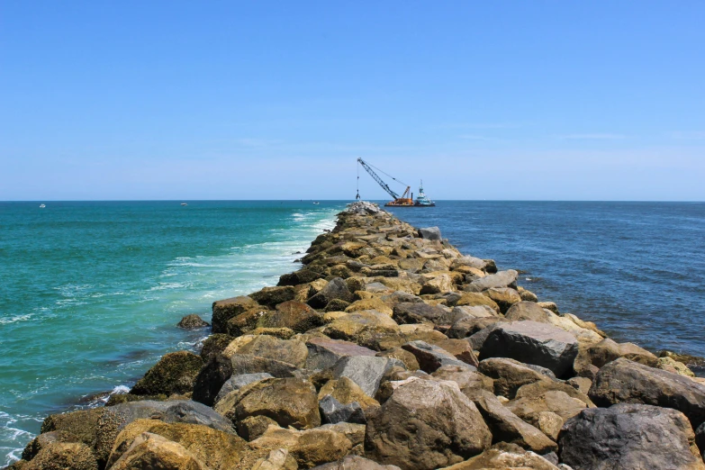 an ocean view with water and rocks along a line