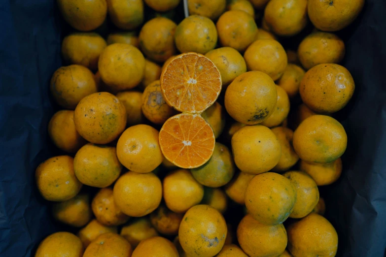 an orange is placed in a pile with other fruit