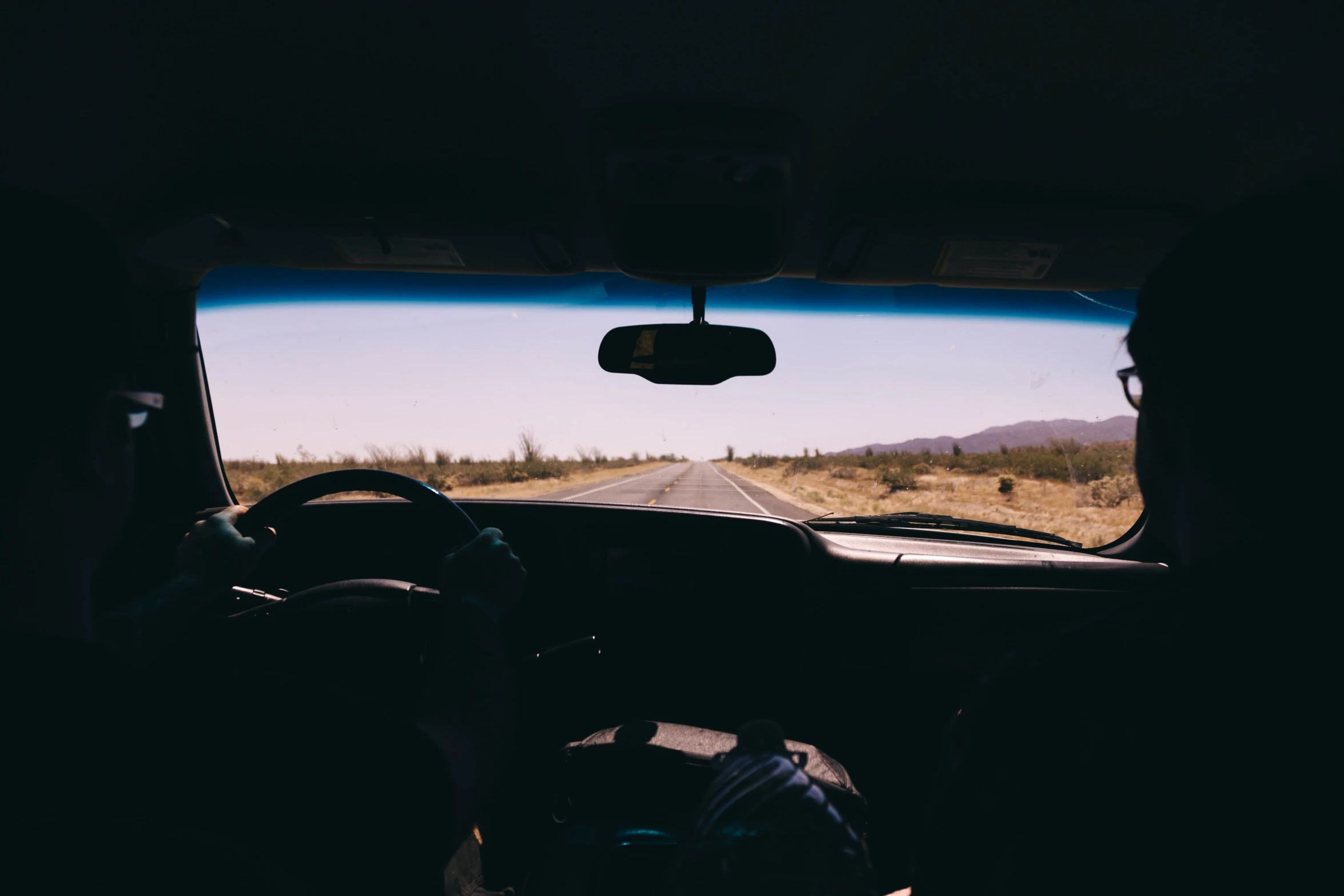 a view from inside the front seat of a car as a man drives by on an open road