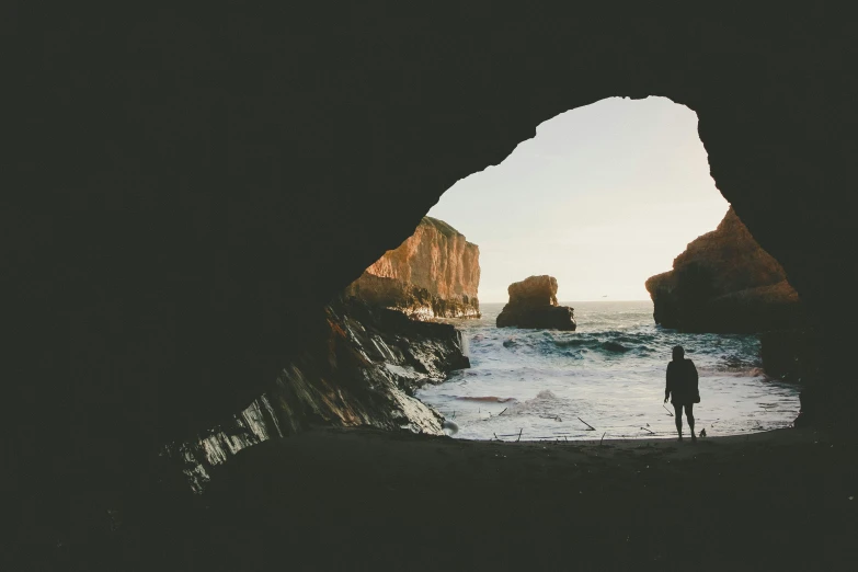 person standing on a rocky cliff looking out at the water