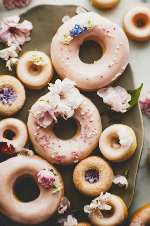 a bunch of doughnuts on a plate with flowers