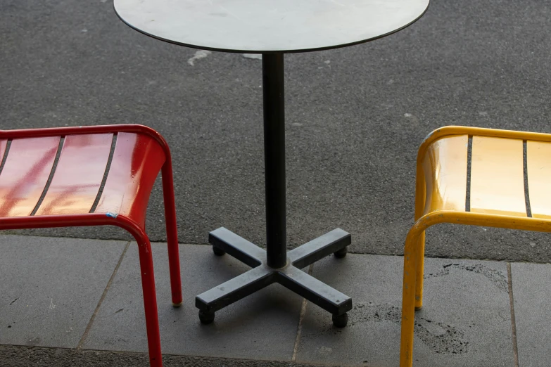 there are two chairs and a table on the sidewalk