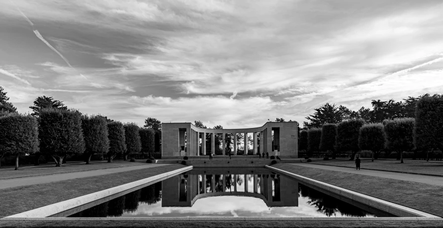 black and white po of trees, water, and a building