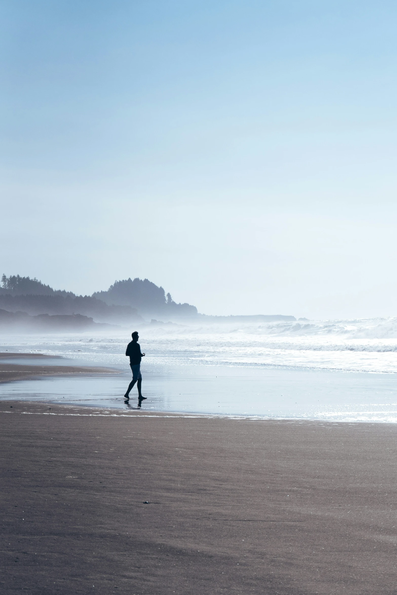 a man walking along the ocean with his surfboard