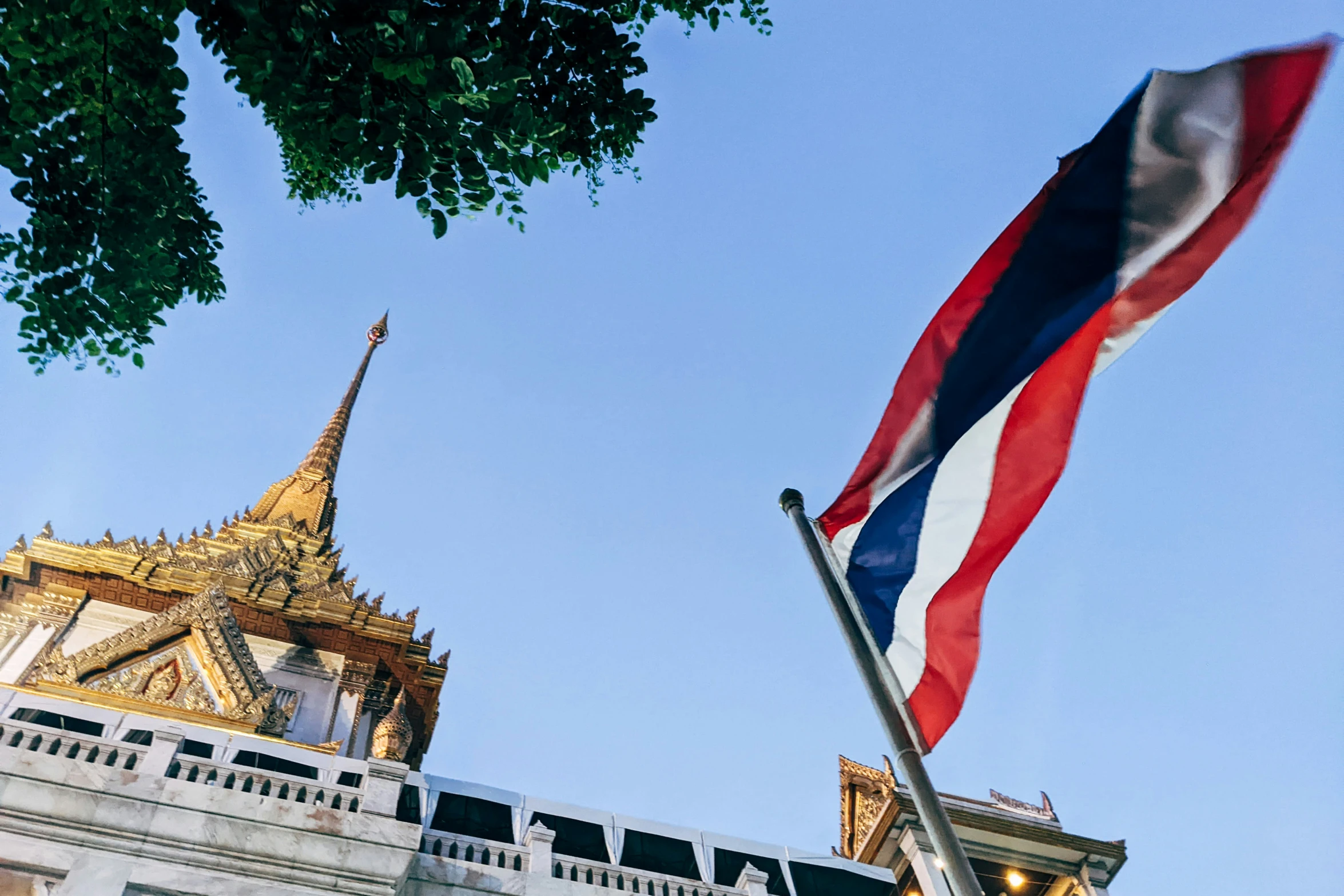 a tall spire is in the distance and two flags are in front