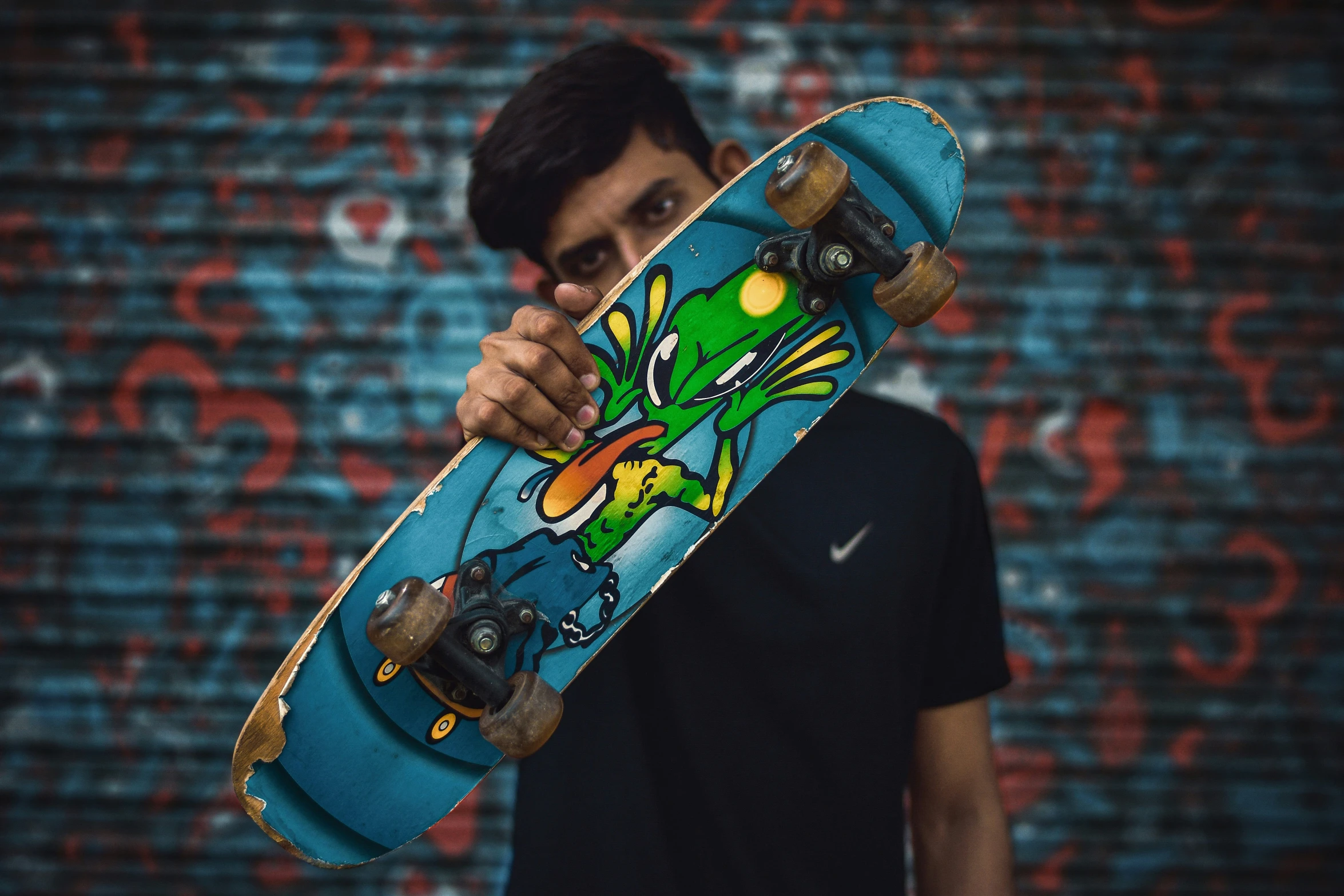 man with skateboard standing near the wall in front of camera