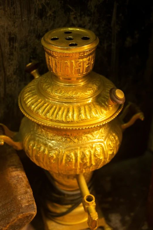 a golden vase sitting on top of a wooden table