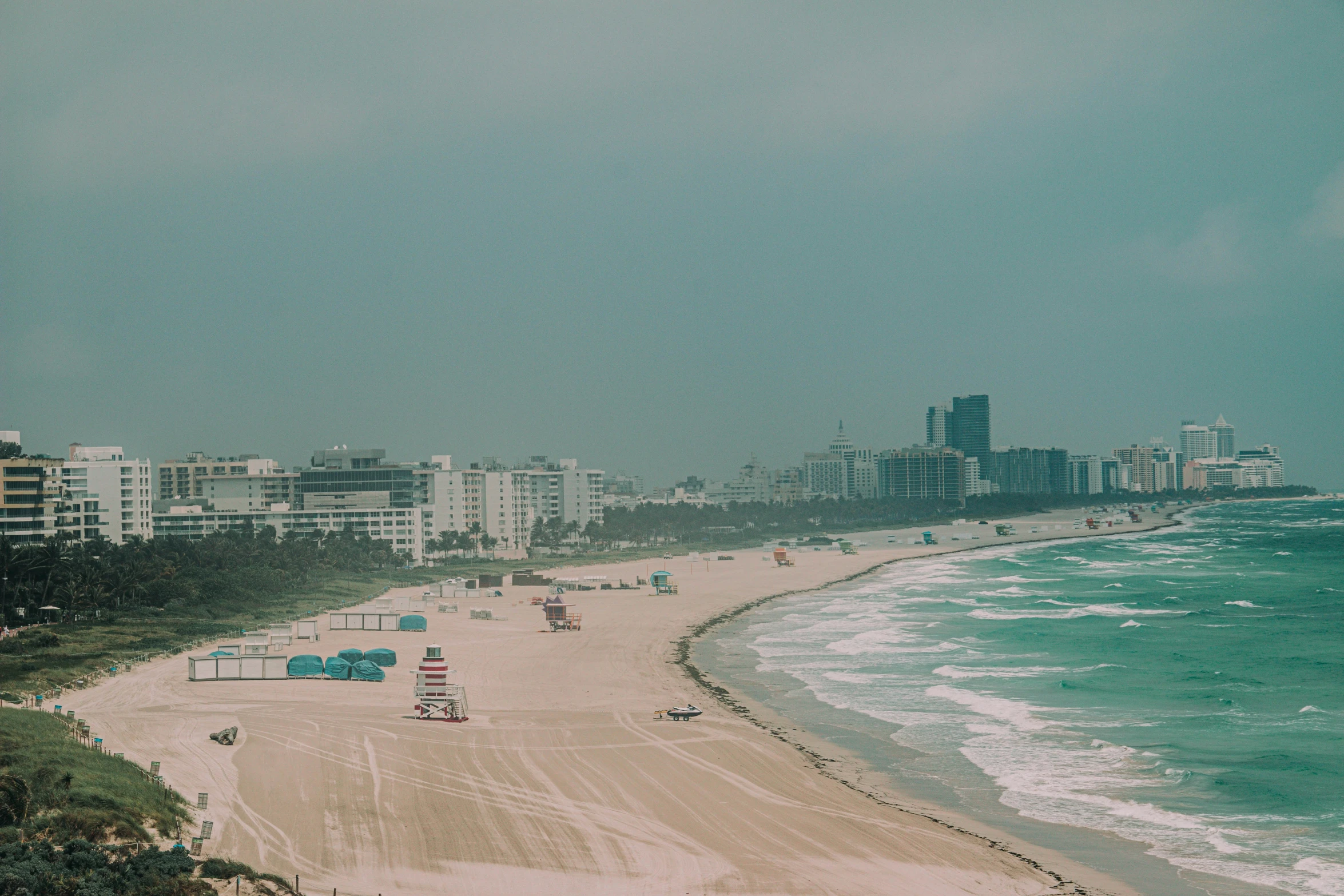 a sandy beach lined with tall buildings near the ocean