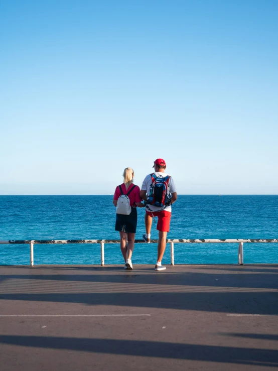 a couple is sitting on the pier near water