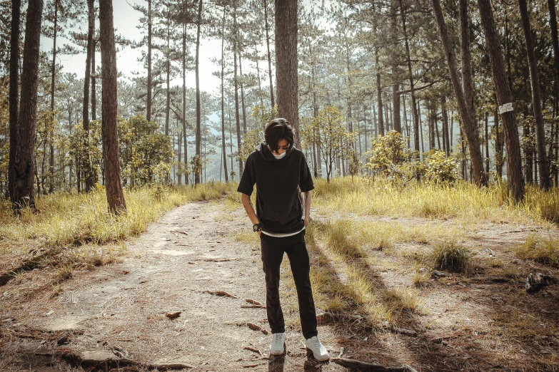 a young man standing on the middle of a dirt road