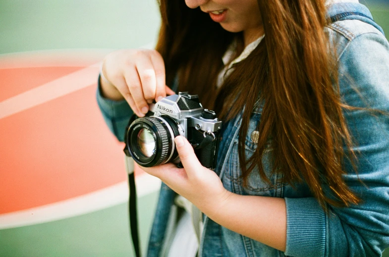 woman in jacket holding up an old film camera