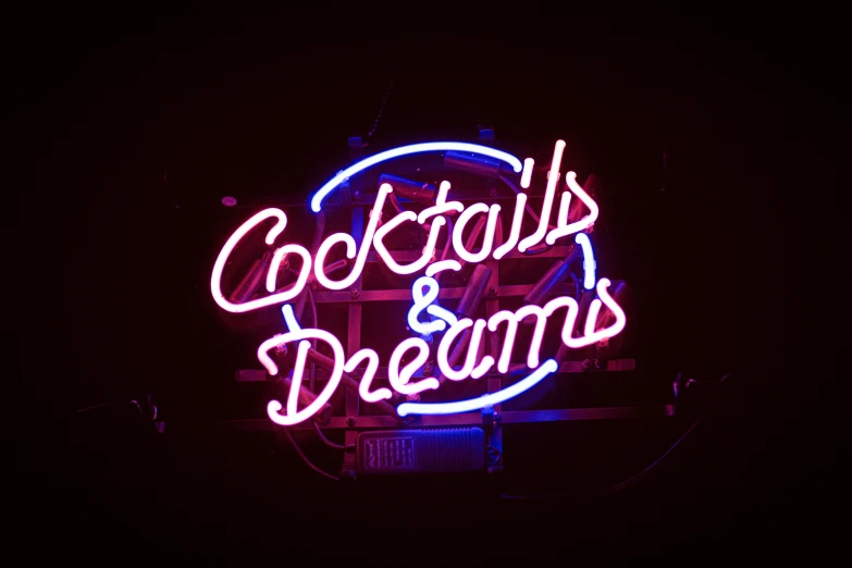 the neon sign reads cocktails and dreams on the black background