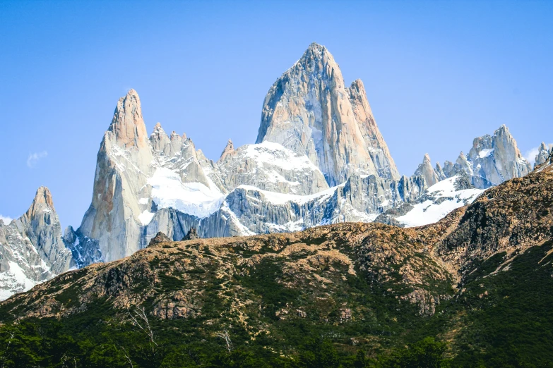 three very tall mountains are against a blue sky