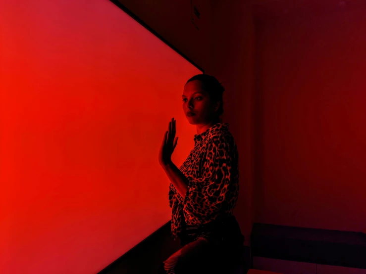 a woman standing near a wall holding her hands up