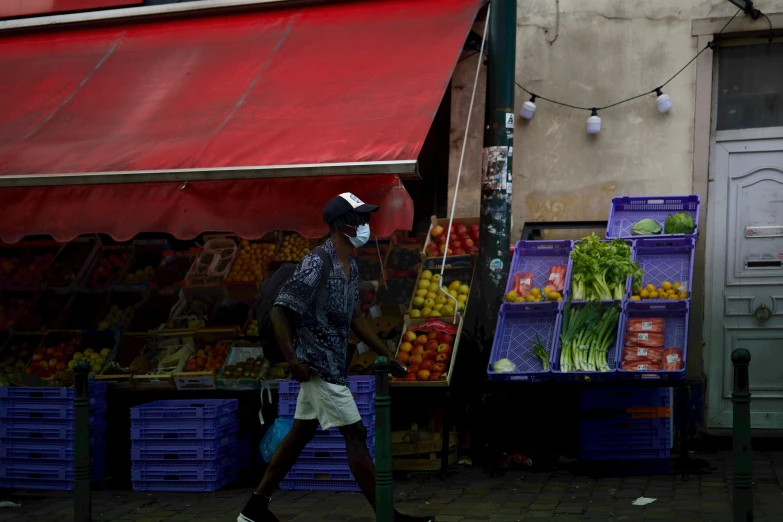 a man is walking down the sidewalk next to an outdoor market