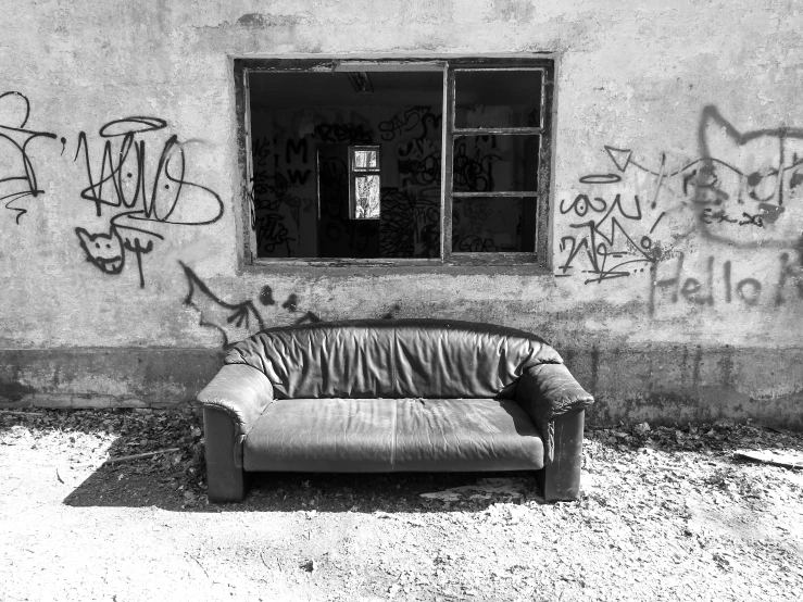 a couch sitting in front of a window with graffiti