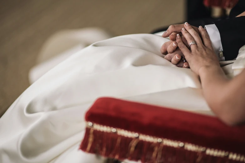 couple on wedding day, touching hands under their wedding veil