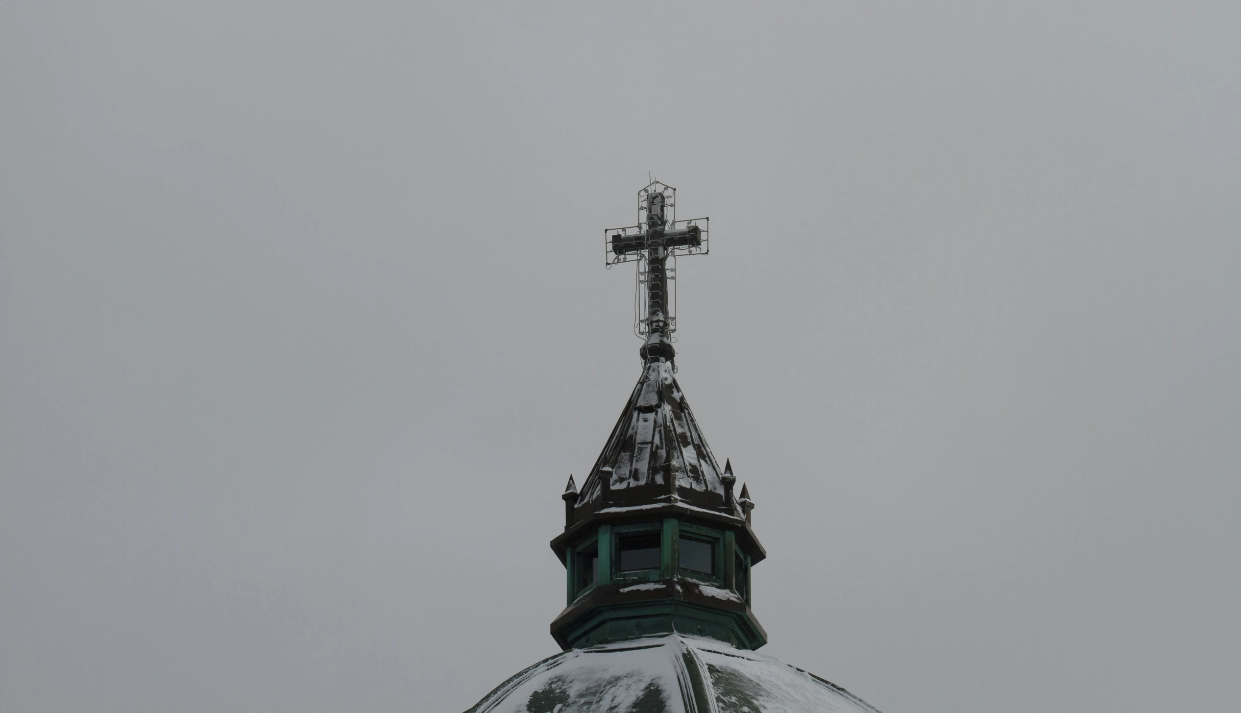 a steeple with a cross on top that looks to be snow