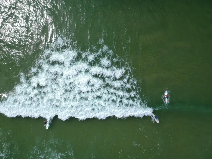 people ride surf boards on the water near an object that looks like an airplane