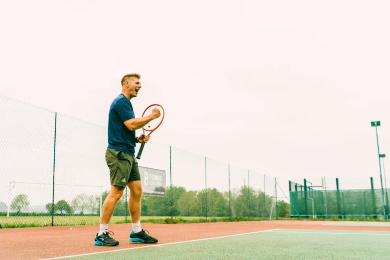 a man holding his tennis racket standing on a court