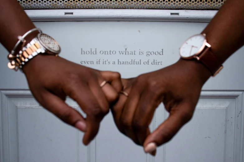 two hands with ring on their fingers are standing next to a door