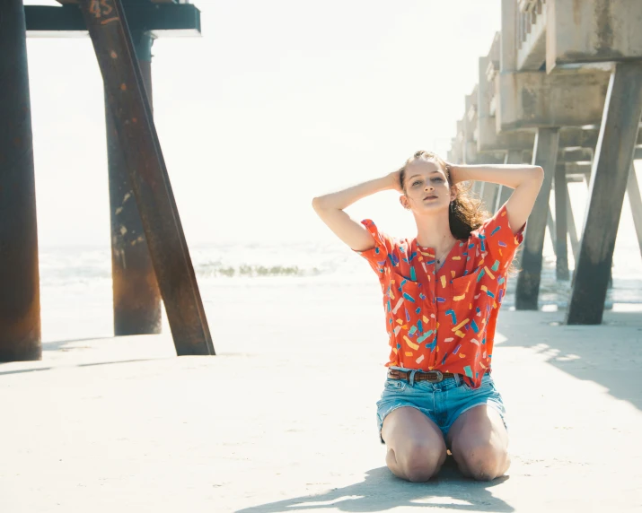 a woman in shorts is sitting by the ocean