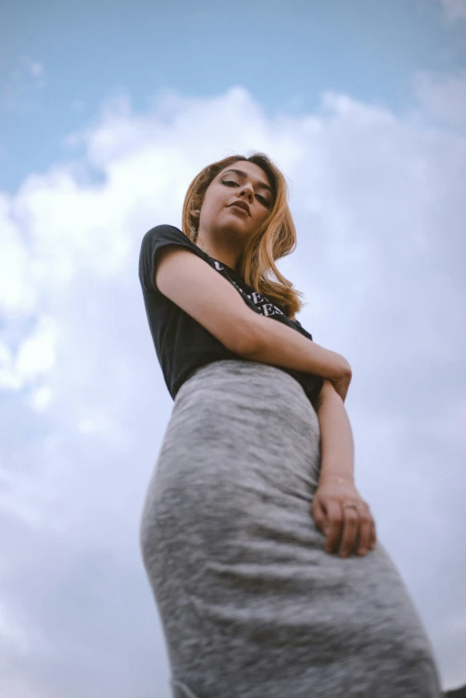 a woman is standing under a cloud - filled sky