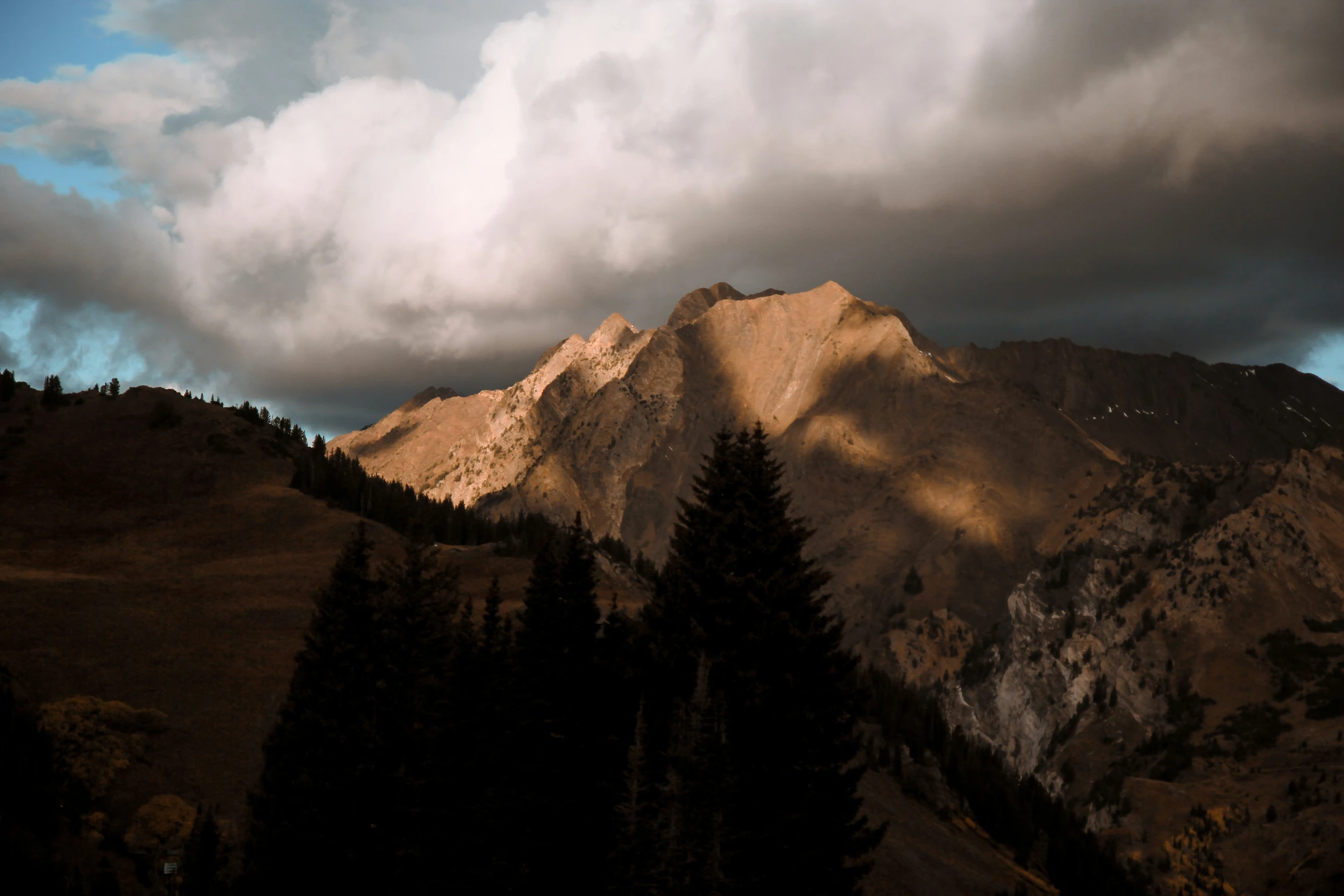 the mountains are covered by thick clouds, and the sunlight is reflecting on the snow - capped peaks