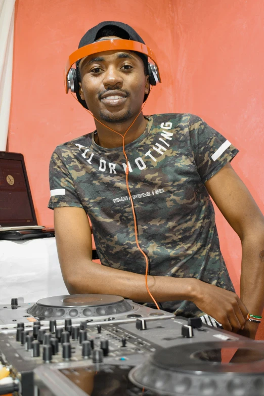 a black man in headphones sits at a dj booth