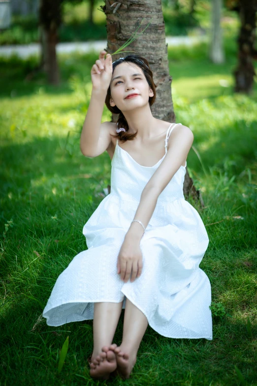 the woman is sitting under a tree posing for a po