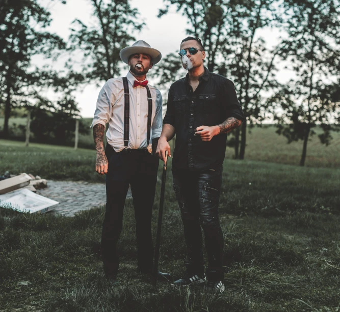 two men standing in the grass wearing tuxedo outfits