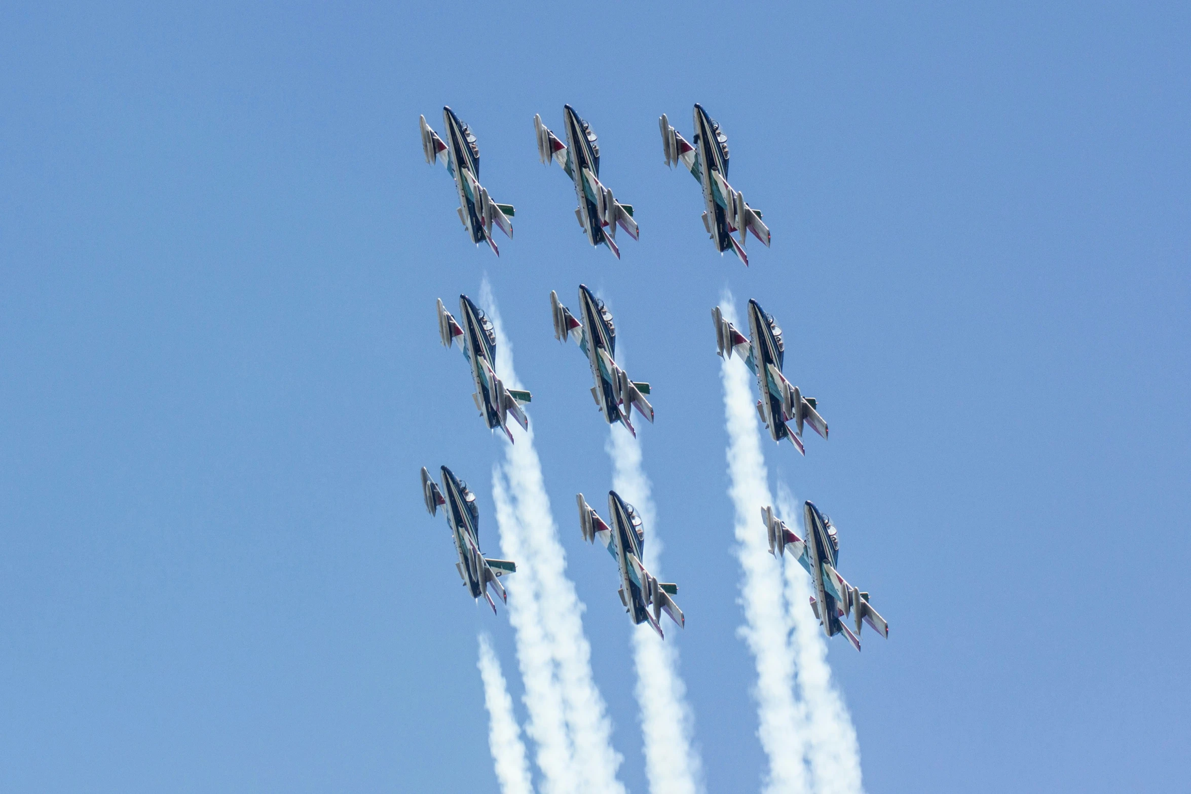 six airplanes with a white cloud trailing through the sky