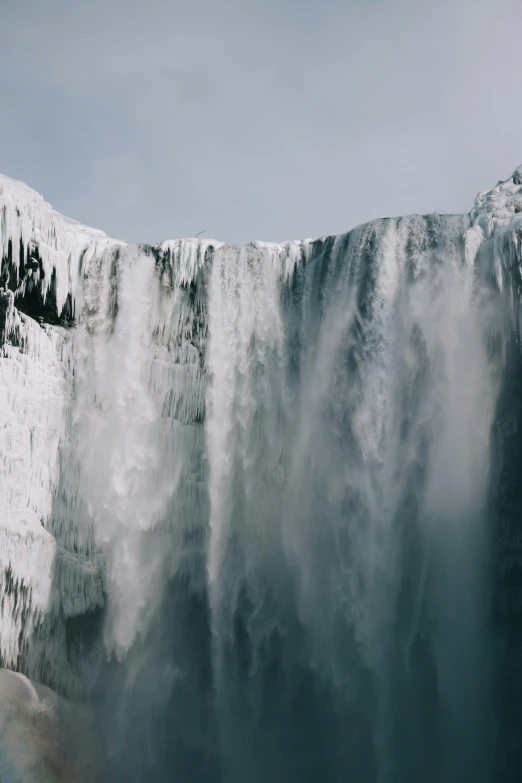 a large waterfall with lots of water and snow on the side