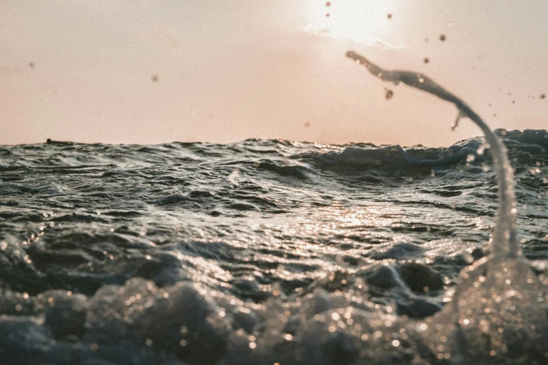 an ocean wave and a sun with some sky in background