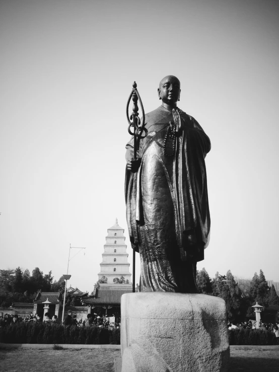 an asian statue is sitting in front of a pagoda