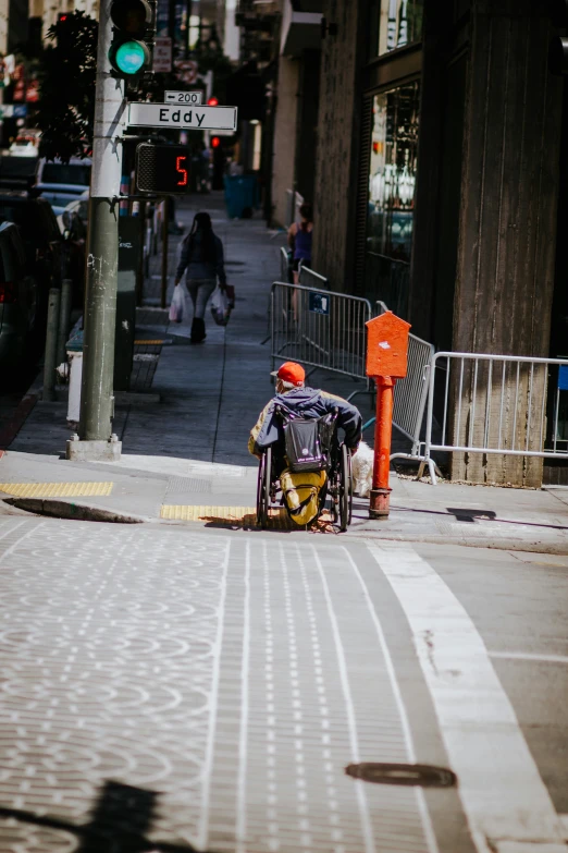 a man in a wheel chair is sitting on the sidewalk