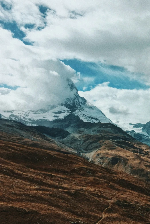 the snow covered mountains and hills have brown and green grass