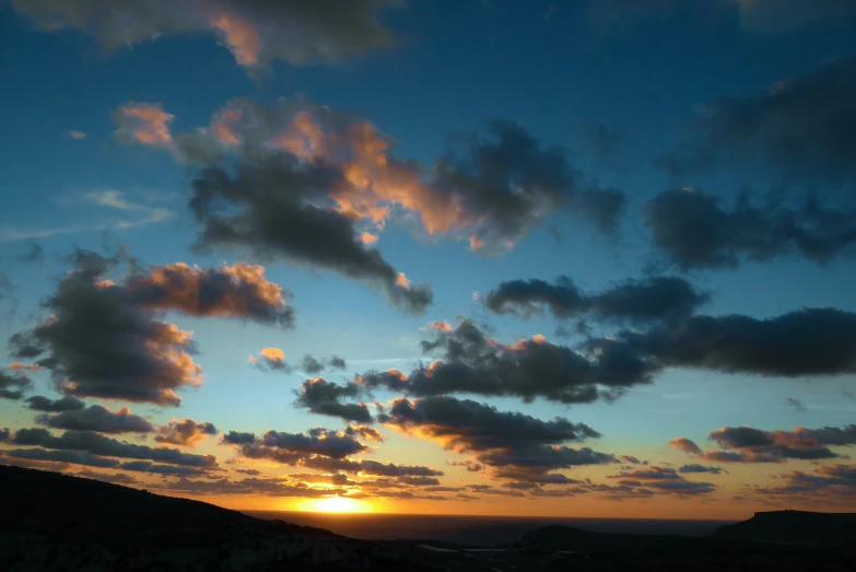 the sunset reflecting its colors as seen from an area of rocky terrain